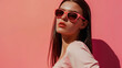 © VK Studio - A woman in a pink outfit and pink sunglasses poses against a vibrant pink background, striking a confident and stylish pose.