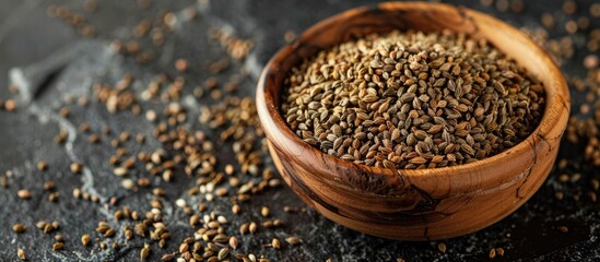 Poster - Ajwain seeds closeup in a wooden bowl on a dark slate backdrop with room for more elements in the image. Creative banner. Copyspace image