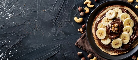 Poster - Delicious thin pancakes with chocolate paste sliced banana and nuts on a black wooden background set against a blank space for text or images. Creative banner. Copyspace image