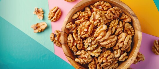 Aufkleber - Close up top view of walnut kernel halves in a wooden bowl on a colorful background Illustrates healthy eating with a focus on walnuts as superfoods with copy space image