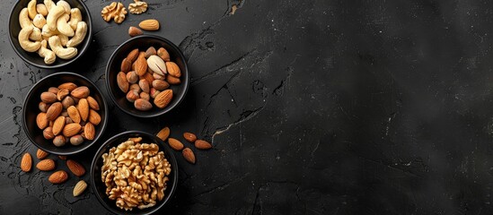 Aufkleber - A black table displaying four bowls filled with various nuts like cashews almonds walnuts and pistachios offering a top view with a blank area for additional content a copy space image