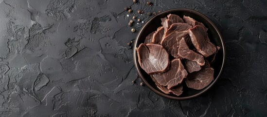 Poster - Beef liver slices in a bowl on black surface with copy space image