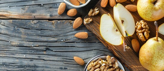 Poster - Bright background with sliced pear almonds walnuts on a wooden board depicts a healthy and vegetarian diet concept in a top view copy space image