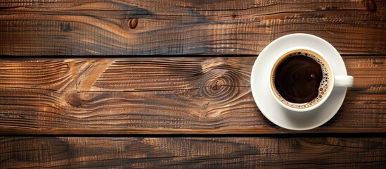 Poster - A coffee cup positioned from above on a wooden table with copy space image available
