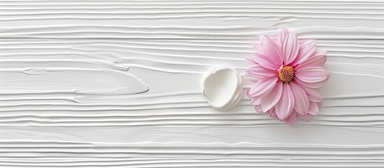 Poster - A cosmetic cream displayed on a white wood table with a delicate pink flower and ample copy space image