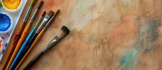 Aufkleber - Colorful watercolors on brown paper with a plastic palette holding painter s brushes Copy space image