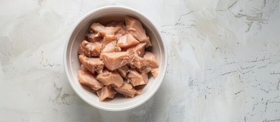 Poster - Top view of canned tuna in a white bowl on a white background with soft lighting in a studio shot allowing for copy space in the image