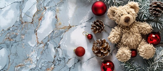 Poster - Christmas themed flat lay with a festive arrangement of pine cones red baubles and a teddy bear on a marbled background creating a cozy holiday copy space image