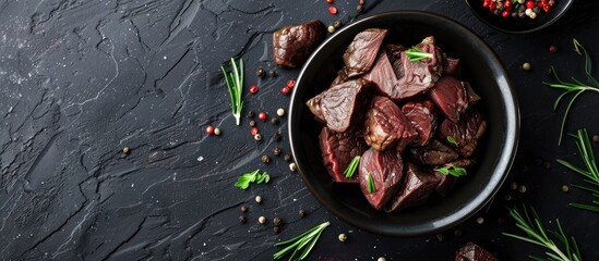 Poster - Beef liver slices in a bowl on black surface with copy space image