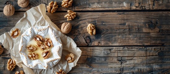 Poster - Top down view of Camembert or Brie cheese wrapped in paper with walnuts on a wooden surface for background allowing for copy space image