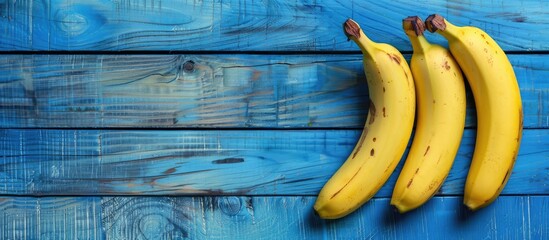 Poster - Bananas ripe and ready to eat arranged on a blue wooden table with copy space image available