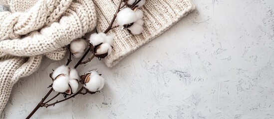 Poster - Display of cozy knitted garments with a cotton branch for a copy space image