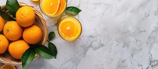 Aufkleber - Top down view of a basket containing oranges with leaves accompanied by a glass of orange juice set on a bright background with ample copy space image