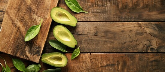 Poster - Avocado slices with leaves displayed on a wooden cutting board with ample copy space image