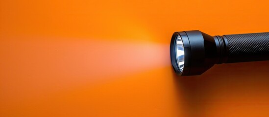 Poster - A black flashlight on an orange background with light shining on the way leaving room for text or images. Creative banner. Copyspace image