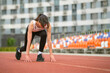 © yavdat - A fit woman crouches at the starting line, her muscles tense and expression determined. This image reflects the importance of preparation and focus in achieving fitness goals.