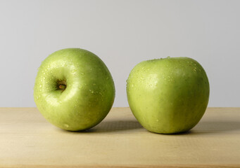 Close-up of two fresh green apples with water drop on wood cutting board, South Korea
