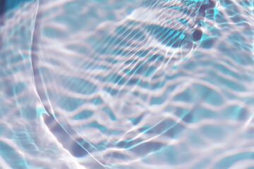 Blue water with ripples on the surface. Defocus blurred transparent blue colored clear calm water surface texture with splashes and bubbles. Water waves with shining pattern texture background.