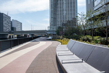 Tokyo city, concrete bench outdoors and paved sidewalk by the river canal, high rise buildings, Japan