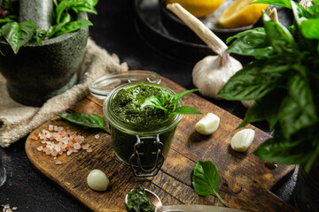 Wall Mural - Green basil pesto sauce in a glass jar on the table