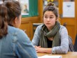 © Ytnart - Two young women engaged in a serious conversation in an indoor classroom setting, focusing on discussion and understanding.