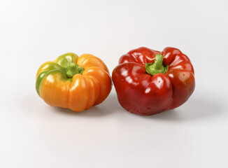 Poster - Close-up of two wet ugly fresh bell peppers with red and orange colors on white floor, South Korea
