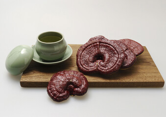 Close-up of two dried raw brown Reishi mushrooms on cutting board with mushroom tea on teacup and lid, South Korea
