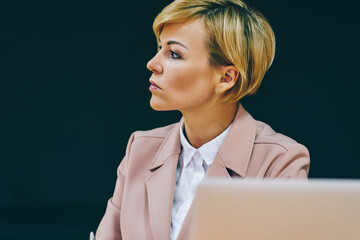 Wall Mural - Thoughtful female entrepreneur 50 years old thinking on ideas for creating successful business plan working at laptop device in office.Pondering mature businesswoman making notes in notebook