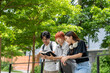 © Wasana - Three young people are standing on a sidewalk, looking at a book