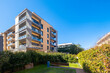 © CarloSanchezPereyra - This image features a modern apartment complex with multiple balconies and a well-maintained green garden in the foreground, reflecting contemporary living and community design.