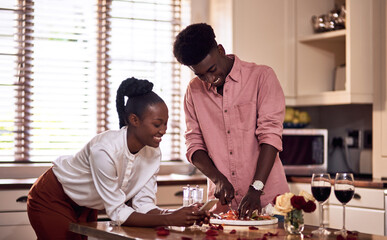 Poster - Cooking, kitchen and black couple in home with wine cutting ingredients for romantic date night meal. Happy, phone and African man and woman preparing dinner or supper together with online recipe.