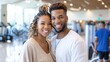 © Lens Legacy - A joyful young couple smiling broadly, standing closely in a well-lit gym setting, exuding happiness, love, and a shared passion for healthy living and fitness.