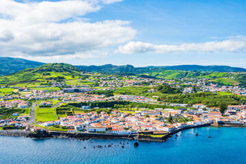 Wall Mural - View of Horta town on ocean coast with green farming hills in background, Faial island, Azores, Portugal