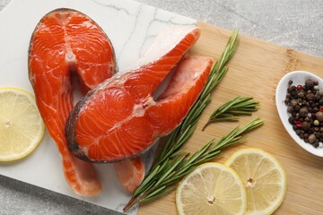 Wall Mural - Board with fresh salmon steaks, peppercorns, rosemary and lemon on grey textured table, top view