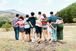 © Lomb - Diverse group of friends embracing outdoors with mountain view, unity and togetherness concept - view from behind