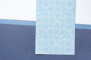 Sticker - paper card with decor pattern on scrapbooking paper pad open to a sheet with dark blue space and white space