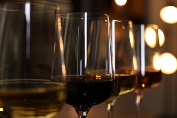 Wall Mural - Different tasty wines in glasses against blurred lights, closeup