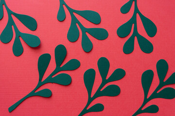 Sticker - stylized die-cut green paper leaves arranged on blank red paper