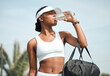 © peopleimages.com - Tennis, drinking water and black woman on court, sports and fitness with nutrition, wellness and workout. African person, outdoor and athlete with bottle racket and training with break and healthy