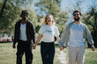 © qunica.com - Carefree and happy, three friends enjoy a sunny day at an urban park, laughing as they walk hand in hand, embodying the joy of friendship and leisure.