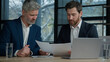© Yuliia - Caucasian men professional businessmen business partners coworkers discussing contract at meeting in office discuss project review paper documents report manager seller offer profitable deal to client