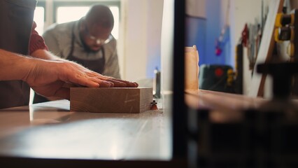 Wall Mural - Man putting lumber block through spindle moulder, creating smooth edges on wooden piece. Joiner using heavy machinery to craft joints for furniture and structures, camera B close up