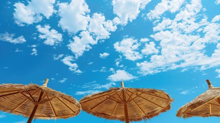 Wall Mural - Natural reed umbrellas under blue sky with clouds Concept of summertime lifestyle and journey