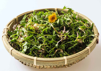 Wall Mural - Close-up of fresh dandelion leaves and yellow flower on bamboo basket, South Korea
