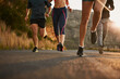 © Sanc/peopleimages.com - Running, road and feet of people in nature for fitness, race and morning cardio at sunrise. Sports, legs and group in street for marathon, training or body performance, speed challenge or competition