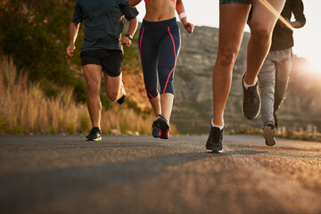 Running, road and feet of people in nature for fitness, race and morning cardio at sunrise. Sports, legs and group in street for marathon, training or body performance, speed challenge or competition