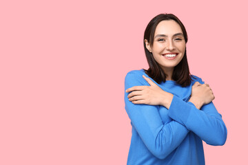 Poster - Young woman hugging herself on pink background