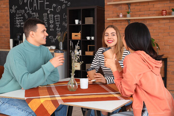 Poster - Group of young friends drinking coffee at table in cafe