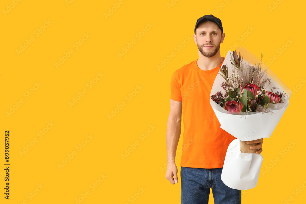 Young delivery man with bouquet of beautiful flowers on yellow background