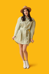 Poster - Beautiful young woman in stylish dress and hat on yellow background